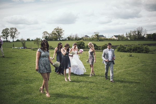 bridal party walking through a field