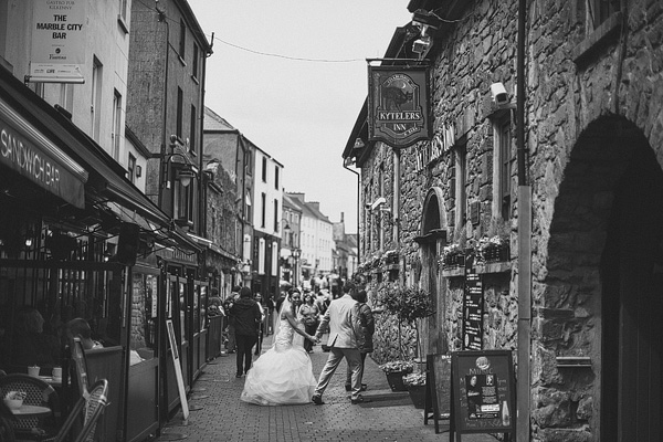 bride and groom walking through village