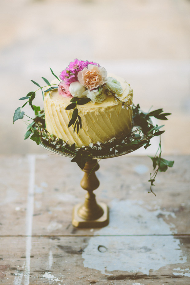 pale yellow lemon wedding cake with flower cake topper on brass cake stand