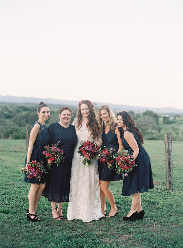 Beautiful bride in lace with gorgeous bridesmaids in black dresses and red bouquets | onefabday.com