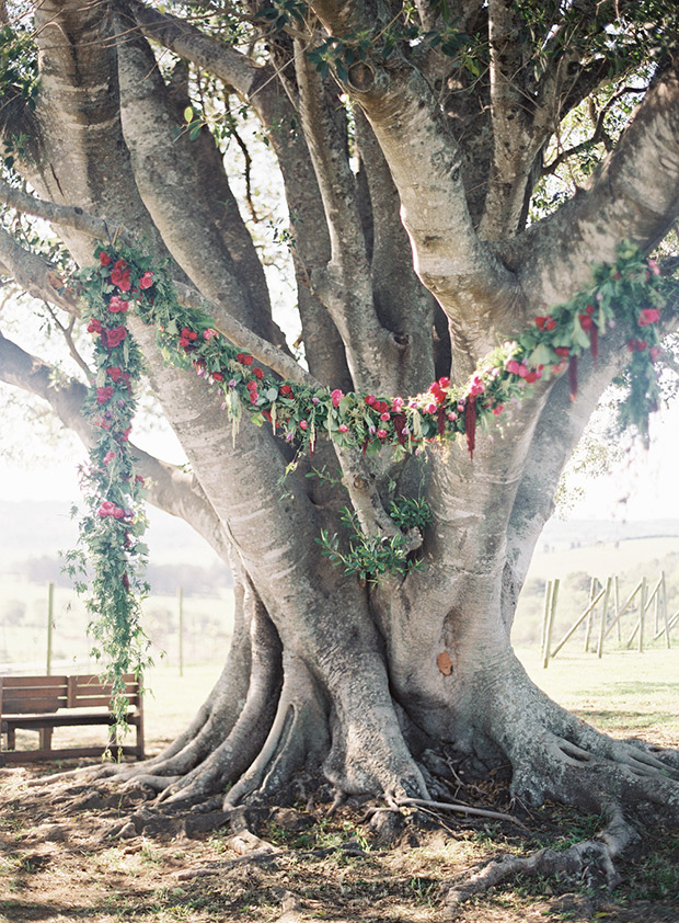 Under a wedding tree, outdoor wedding ceremony location under a beautiful red floral garland  | onefabday.com