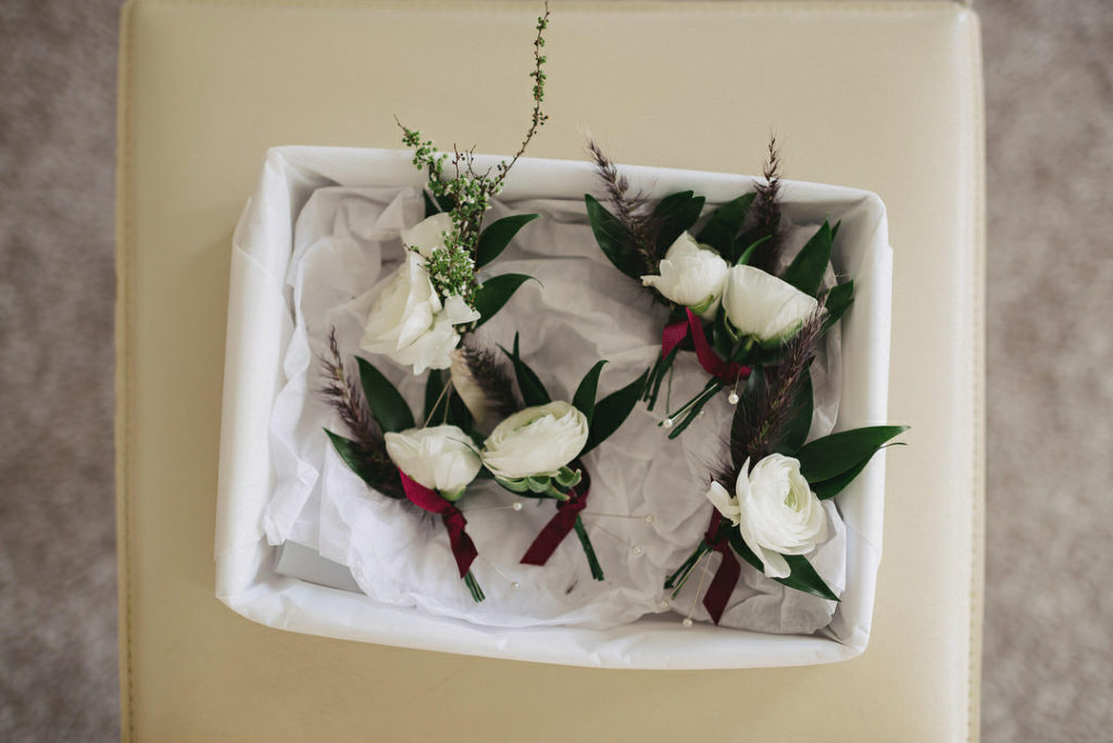 white rose boutonnieres burgundy ribbon