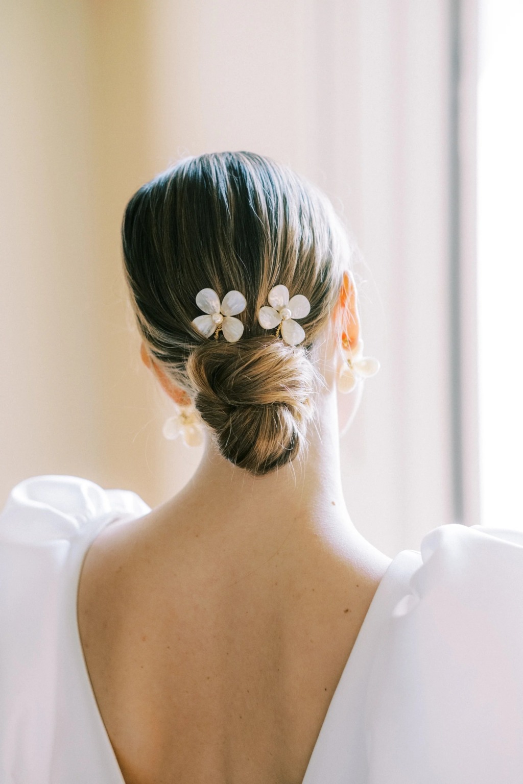 A model wearing two Megan Therese floral and pearl hairpins with a wedding dress with puffed sleeves