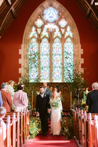 Bride and groom walking down the aisle guests inside church ceremony