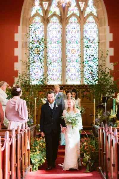 Bride and groom walking down the aisle guests inside church ceremony