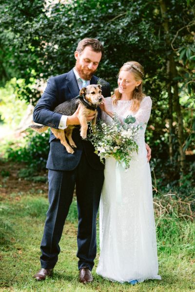 Couple holding dog bouquet flowers bride groom