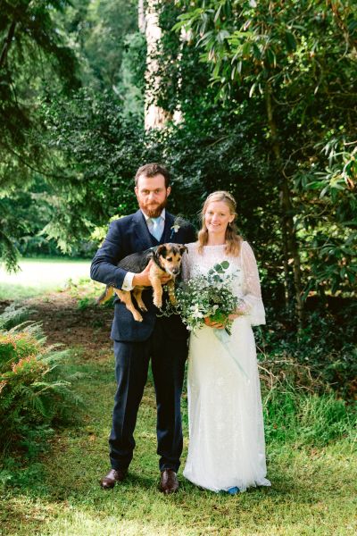 Couple holding dog bouquet flowers bride groom