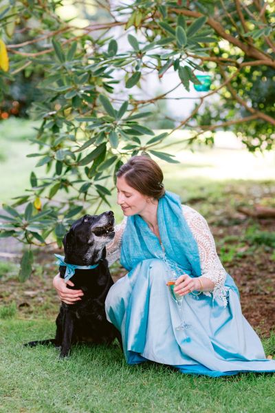 Blue bridesmaid dress blue ribbon on dogs neck petting hugging