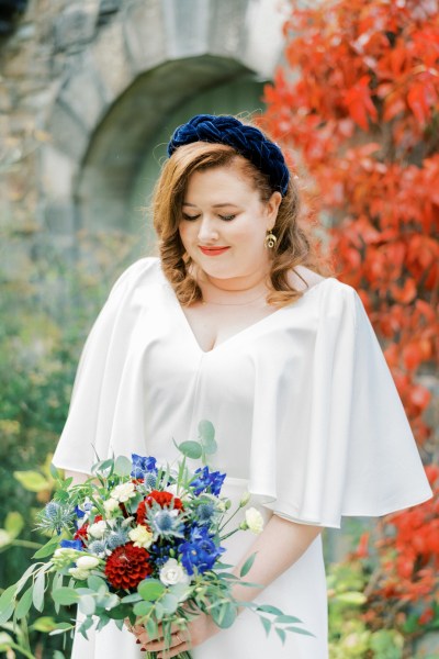 Close up bride holding bouquet of flowers roses headband looking down