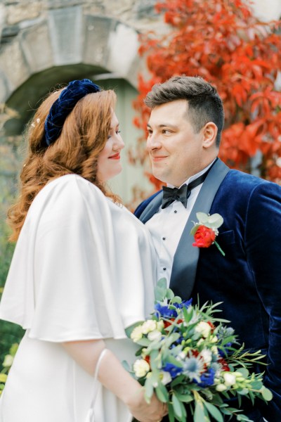 Bride and groom looking at each other holding bouquet of flowers exterior shot