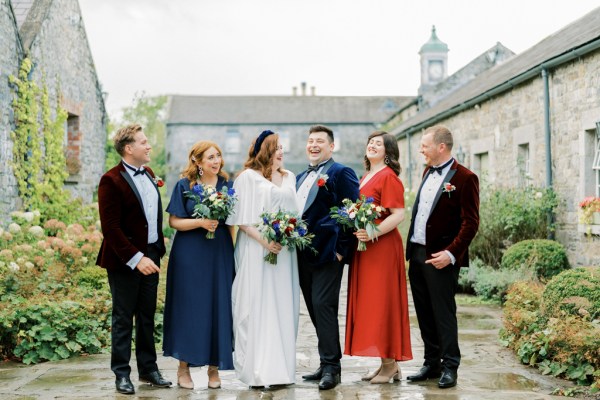 Bride groom family groomsmen bridesmaids bouquet of flowers laughing