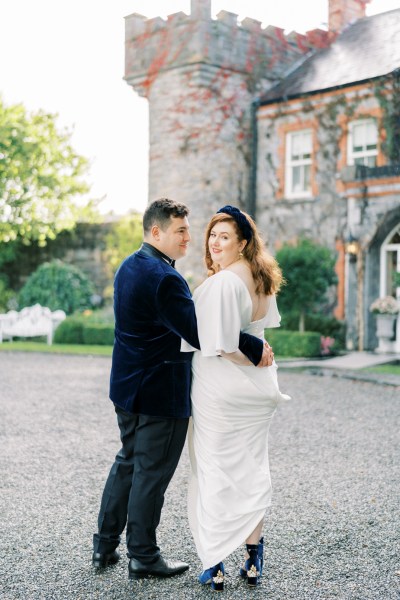 Bride and groom looking over shoulder exterior castle hotel