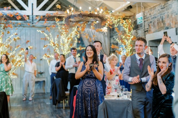 Guests clapping interior lights suit dresses wine table