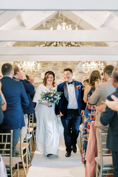 Bride and groom walking down the aisle guests clapping celebration just married happy