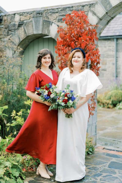 Bride and maid of honour bridesmaid laughing holding bouquet of flowers roses headband red