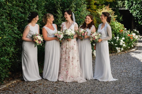 Wedding photography Jane & Alex bride with bridesmaid smiling laughing exterior candid