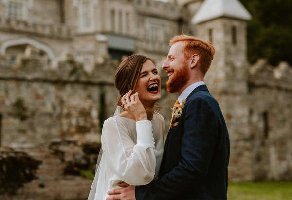 bride and groom laughing at castle outdoors