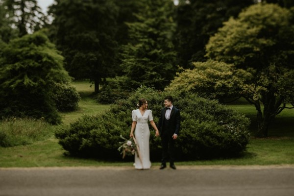 Bride and groom holding hands bouquet of flowers roses forest park exterior background shot