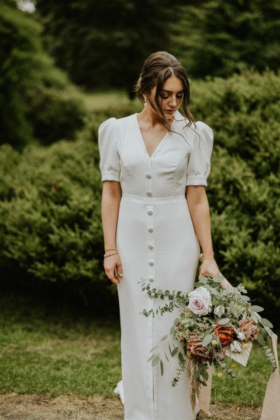 Bride on her own in park holding bouquet of flowers