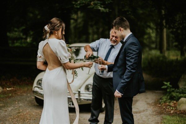 Pouring bride and groom champagne glasses prosecco wedding car in background