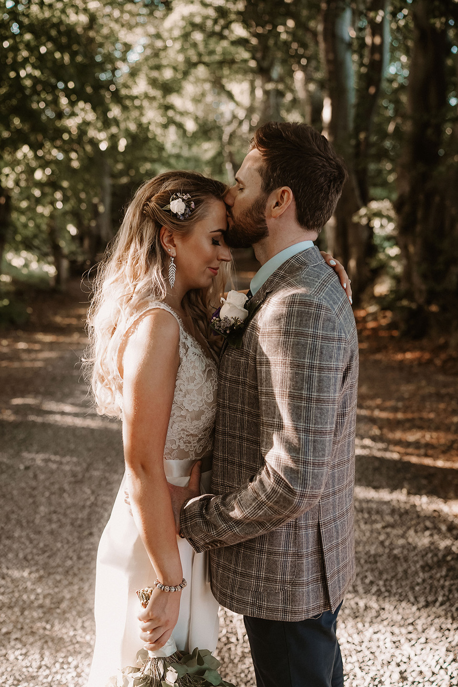 Mark and Lauren's Real Wedding bride groom embracing holding forest sunshine couple flowers forehead kiss