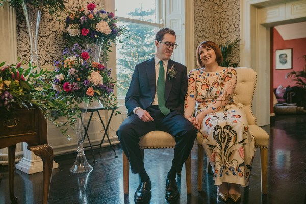 Interior bride and groom floral flowers dress officiant officiate ceremony sitting down