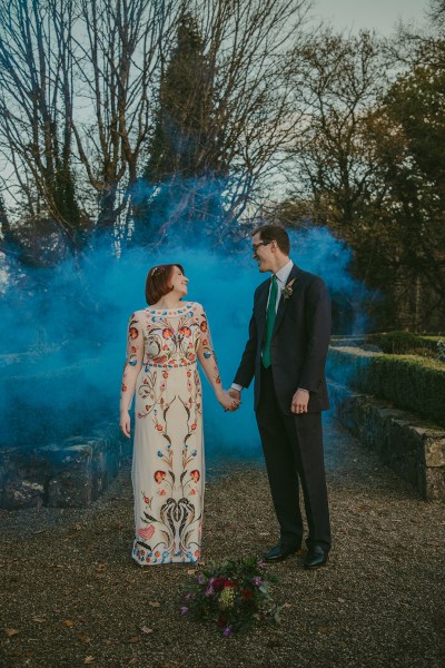 Bride and groom exterior bouquet of flowers exterior garden holding hands blue hue photography smoke