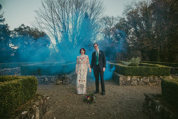 Bride and groom exterior bouquet of flowers exterior garden holding hands blue hue photography smoke