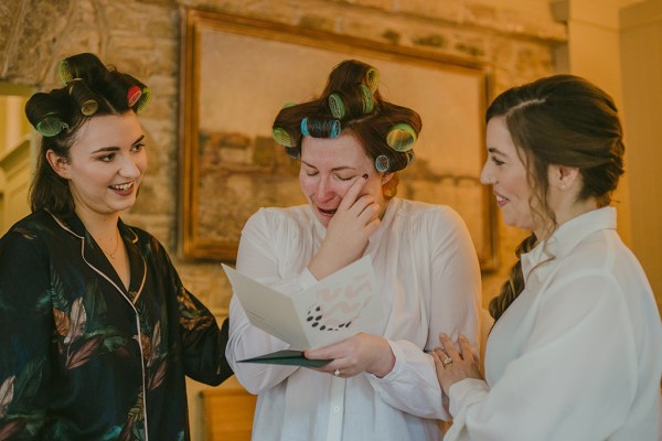 Bride crying reading card with bridesmaids getting ready before ceremony