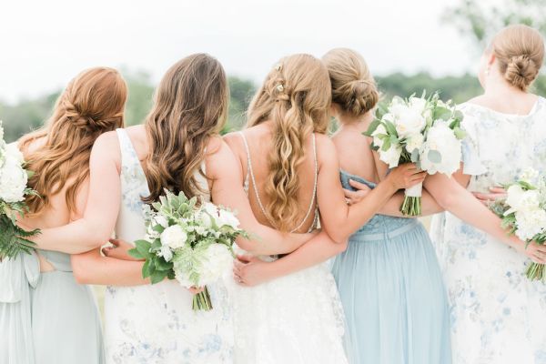 Behind shot of bridesmaids holding hugging each other candid bouquet of flowers