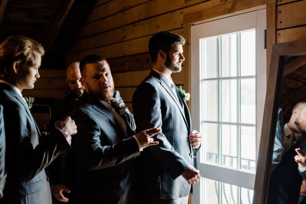 Groom getting ready before wedding ceremony suit jacket mirror window bedroom groomsmen best man