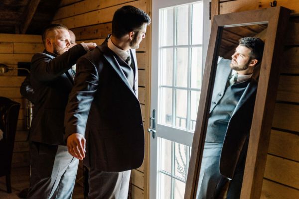 Groom getting ready before wedding ceremony suit jacket mirror window bedroom