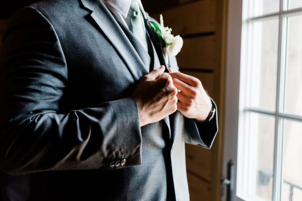 Up close of grooms suit flower watch detail looking out window