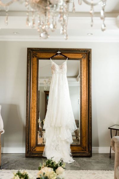 Close up of lace dress hanging up on mirror mr & mrs chandelier elegant shot chair