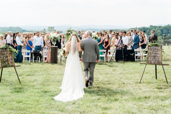 Father of the bride walking down aisle holding bouquet of flowers guests happy smiling clapping welcome to our unplugged ceremony