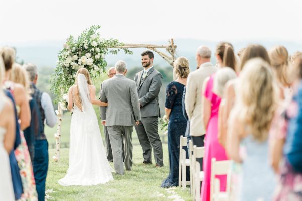 Father of the bride walking down aisle guests ceremony groom veil from behind smiling