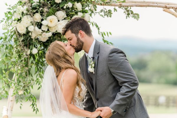 Bride and groom ceremony just wed just married kissing flower floral design in background