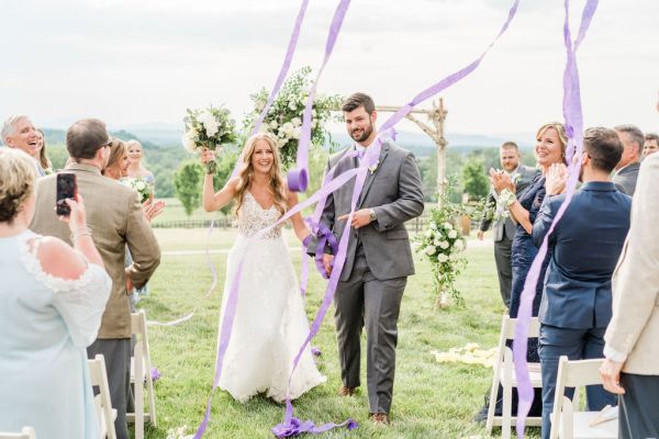 Bride and groom walking down the aisle just wed just married guests clapping ribbon camera phone