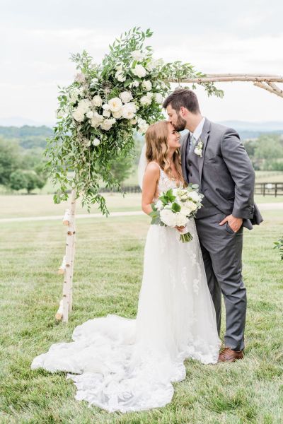 Bride and groom smiling exterior flowers shot bouquet kiss on the forehead