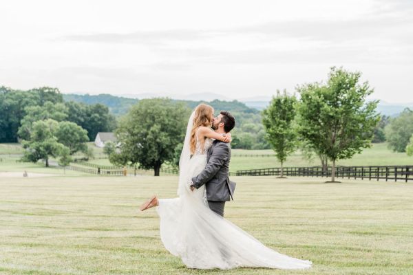 Groom picking bride up exterior farm shot tree veil train dress detail lace