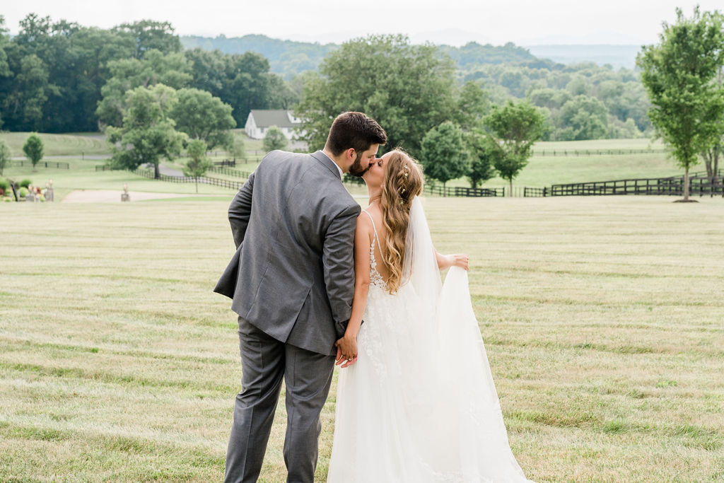 Kissing couple exterior forest park veil dress detail landscape holding hands farm trees