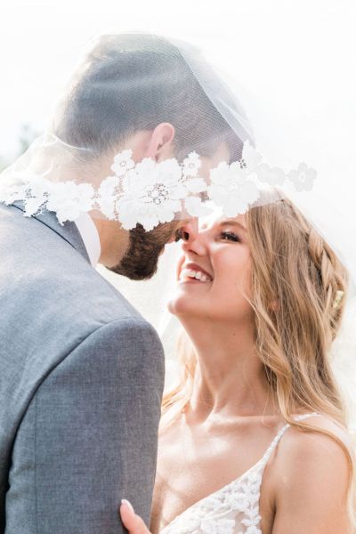 Up close couple under veil dress detail smiling