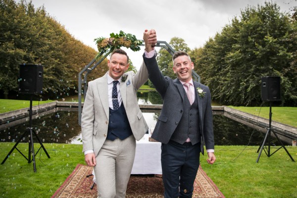 Eoin & Darran Real Wedding grooms hugging couple ceremony hand in hand bubbles