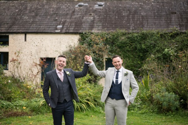 Eoin & Darran Real Wedding hand in hand exterior barn green setting smiling grooms