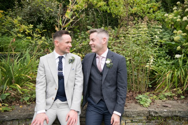 Eoin & Darran Real Wedding grooms smiling exterior sitting green