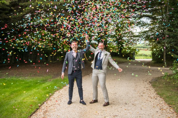 Eoin & Darran Real Wedding confetti couple holding hands exterior path shot laughing smiling