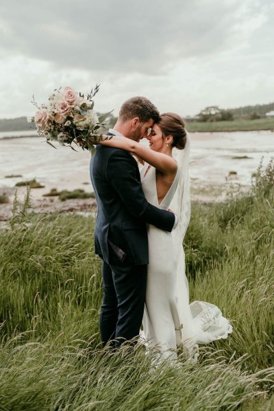 bride and groom on beach and grass