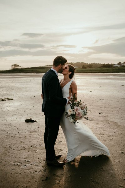 bride and groom kissing on beach