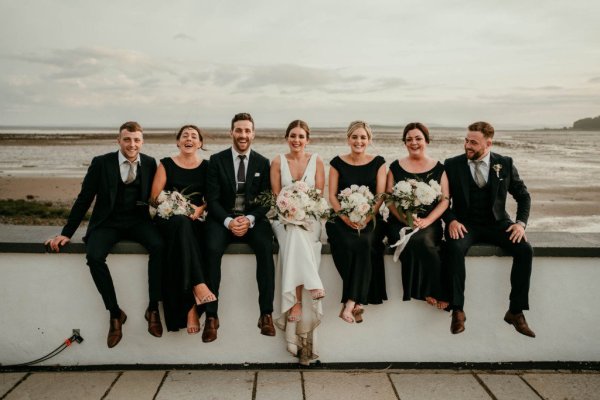 bridal party black bridesmaid dresses sitting on wall