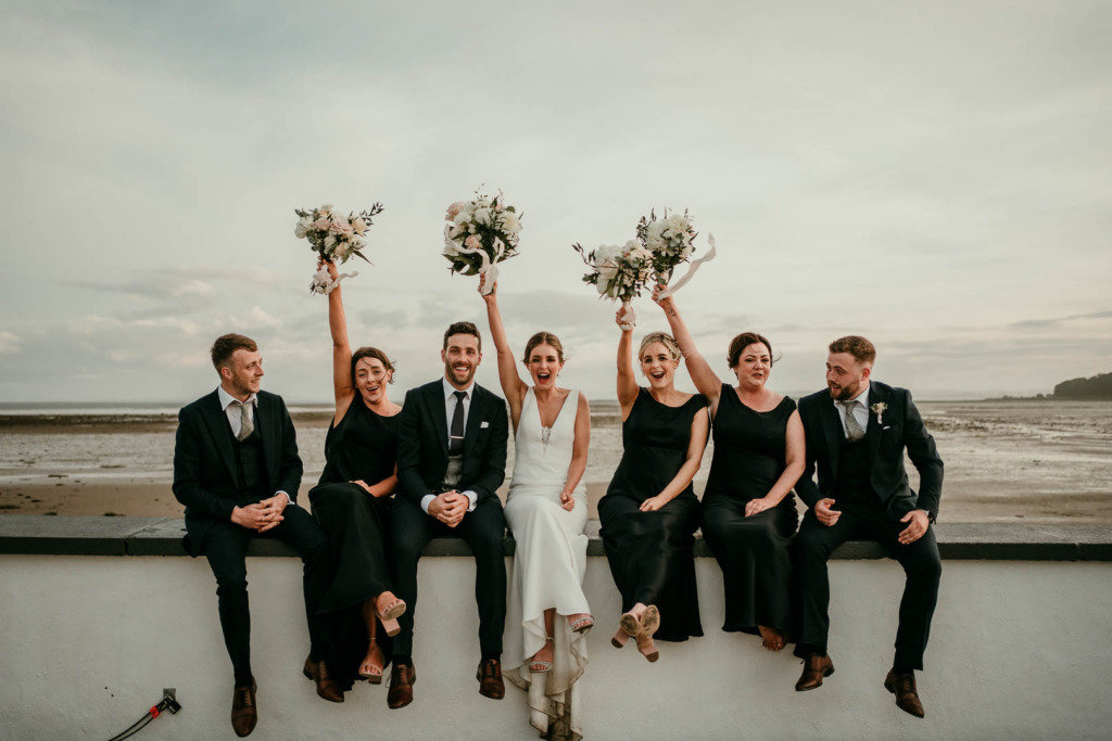 bridal party black bridesmaid dresses sitting on wall